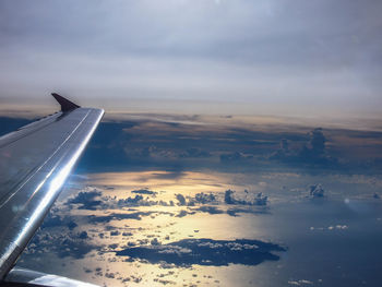 Aerial view of aircraft wing against sky during sunset