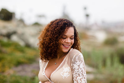 Young woman in sheer dress smiling on beach