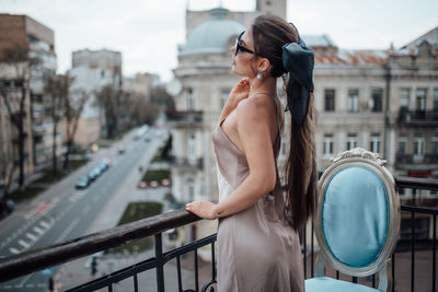 Woman standing by railing in city