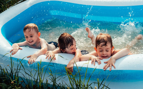 Cheerful happy children lie in the pool and splash with their feet. friends spend summer leisure 