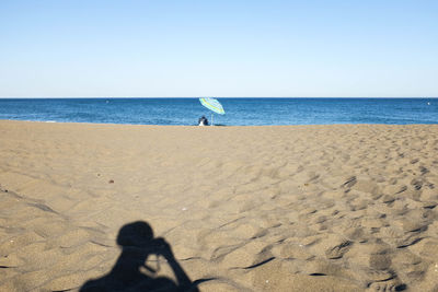 Low section of woman on beach against clear sky