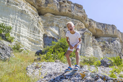 Woman standing on rock against stone wall