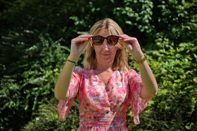 Portrait of woman wearing sunglasses standing against plants