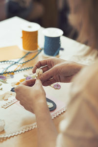 Cropped image of woman making paper flower at table