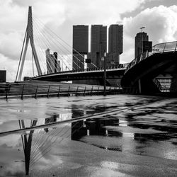 Bridge over river by buildings against sky in city