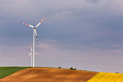 Windmills on hill against sky
