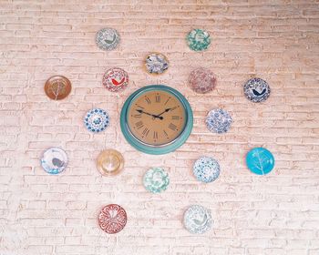 Low angle view of clock amidst colorful plates on wall