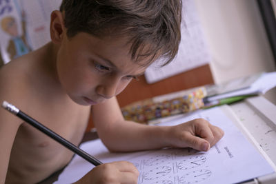 Boy drawing on book at home
