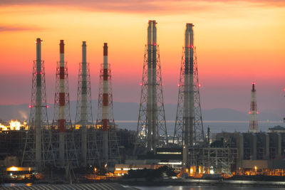 Illuminated factory against sky at sunset