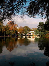House by lake and buildings against sky
