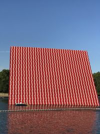 Red floating installation at serpentine lake against clear blue sky