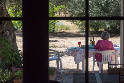 Rear view of an sitting on table by window