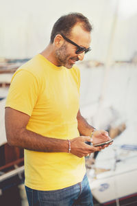 Man using phone while standing at harbor