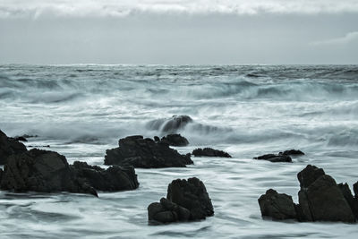 Scenic view of rocks in sea against sky