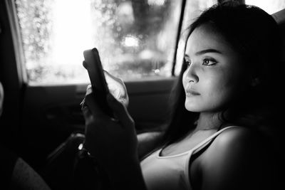 Portrait of young woman looking through window