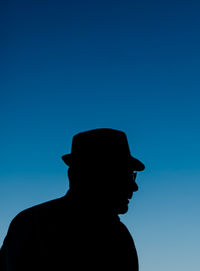 Low angle view of silhouette man against clear blue sky