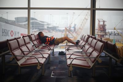 Side view of man sitting on chair in airport