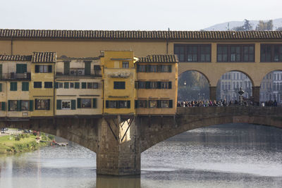 Arch bridge over river against buildings in city