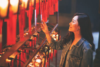 Side view of woman standing at illuminated temple