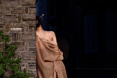 Rear view of woman standing against building