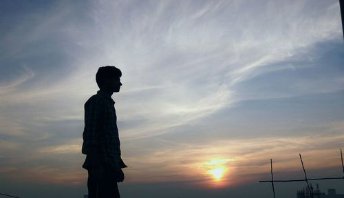 Low angle view of silhouette man standing against sky during sunset