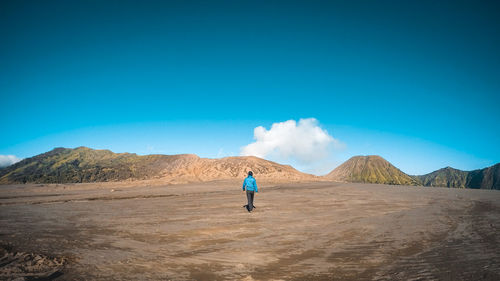 Rear view of man on mountain against blue sky