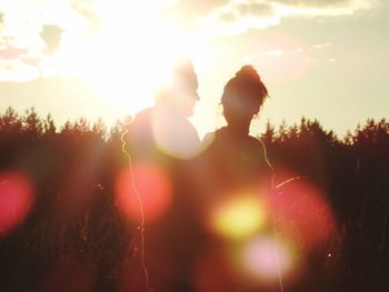 Silhouette people standing on field against sky during sunset