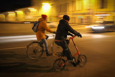 Blurred motion of people riding bicycles on street at night