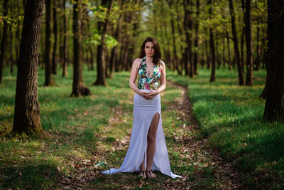 Portrait of young woman standing on tree trunk in forest