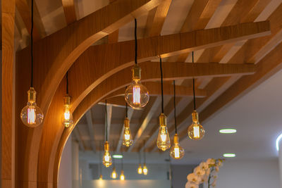 Low angle view of illuminated pendant lights hanging from ceiling