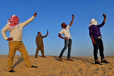 People taking selfie while standing on desert against sky