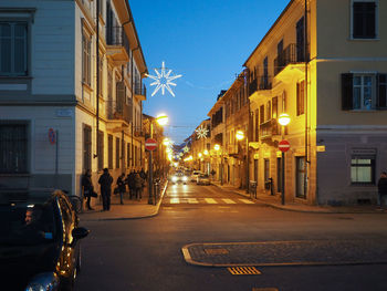 Illuminated street amidst buildings in city at night