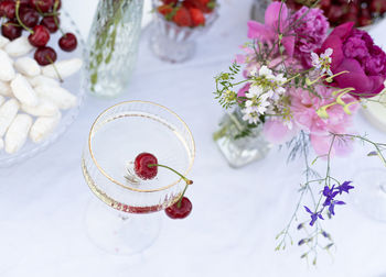 Glass with champagne and cherry inside on table, decorated table