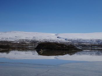 Snow covered landscape against blue sky