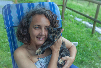 Portrait of woman sitting on a chair holding cute black and orange bay cat