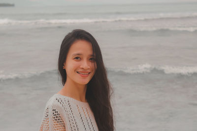 Portrait of young woman standing at beach