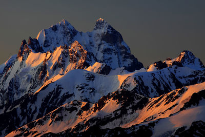 Scenic view of snowcapped mountains against clear sky during sunset