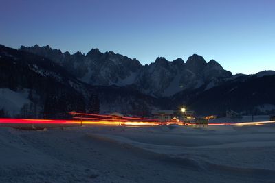 Light trails on street against clear sky at night