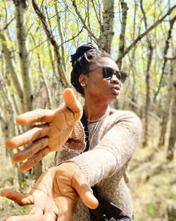 Midsection of woman holding sunglasses in forest