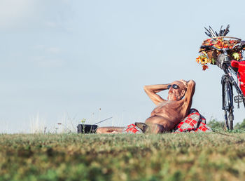 Man lying on field against clear sky