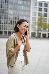 Young businesswoman talking on mobile phone while standing in city