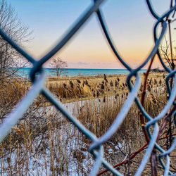 Scenic view of sea seen through chainlink fence