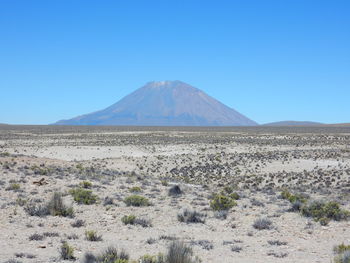 Scenic view of arid landscape against clear blue sky