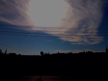 Low angle view of electricity pylon against cloudy sky