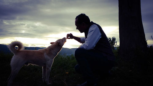 Side view of woman with dog against sky