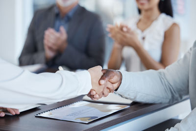 Midsection of business colleagues shaking hands in office
