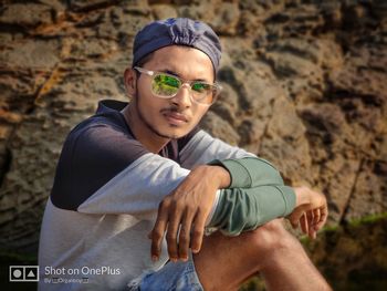 Portrait of young man wearing sunglasses sitting on land