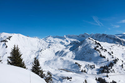 Scenic view of snow mountains against blue sky