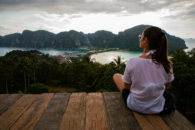 Rear view of woman sitting at observation point against sea