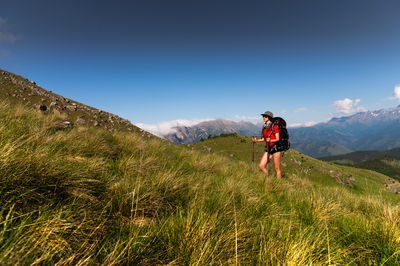 Rear view of man walking on field against clear sky